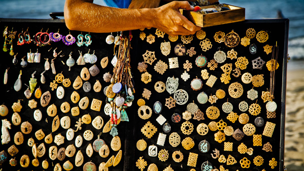-en-a-beach-vendor-offers-carved-stone-pendants-es-vendedor-playero-ofreciendo-pendientes-de-roca-tallada-